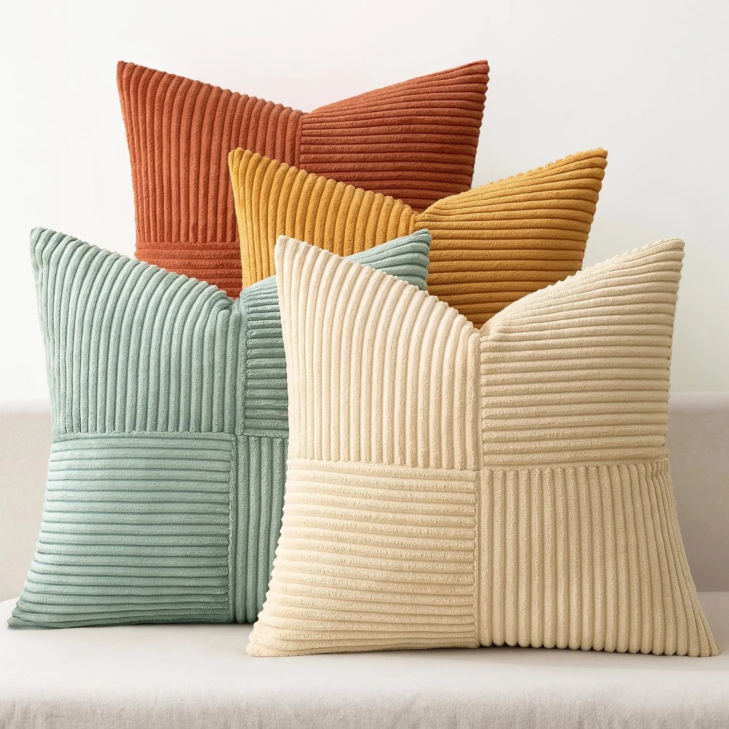 Colorful corduroy pillow covers in green, orange, and beige tones on sofa