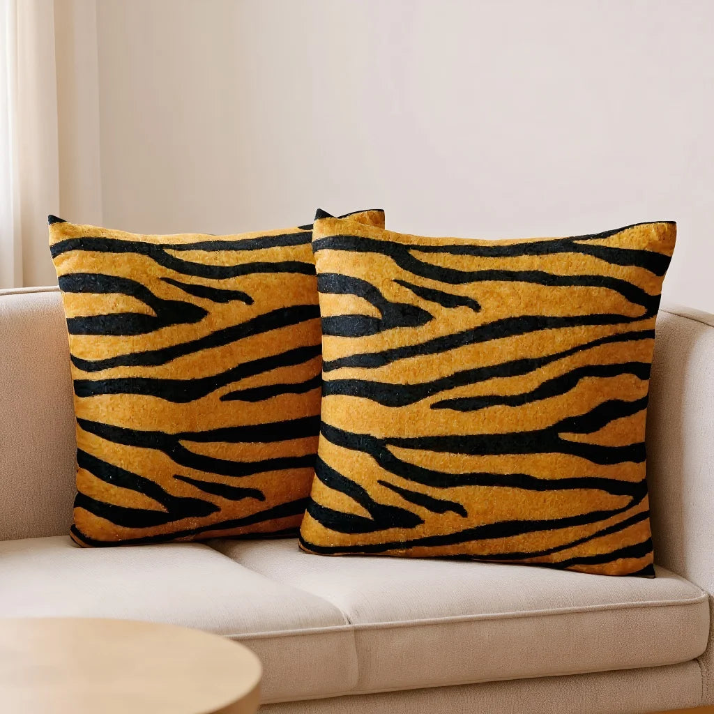 Two tiger-striped pillows on a beige sofa with a neutral background