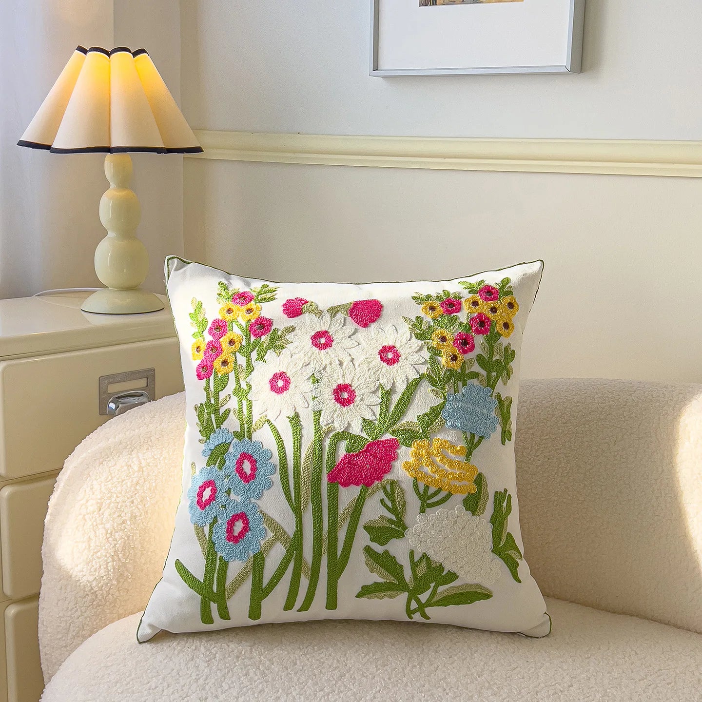 Decorative pillow with floral embroidery on a couch in a room setting.