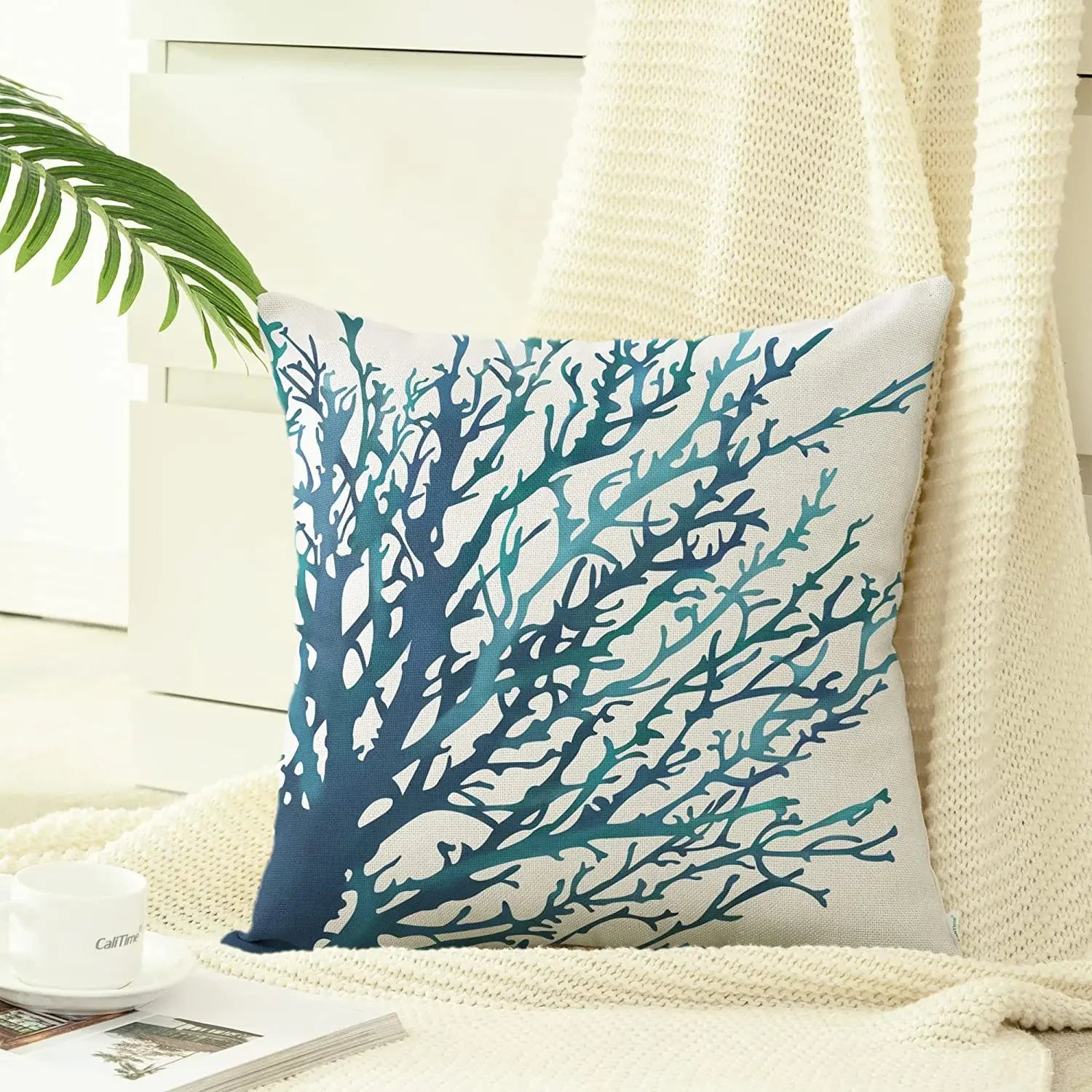 Decorative pillow with blue coral design on a neutral background