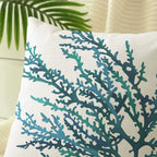 Decorative pillow with teal coral pattern on a beige background