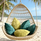 Woven hanging chair with green and yellow cushions on a beach