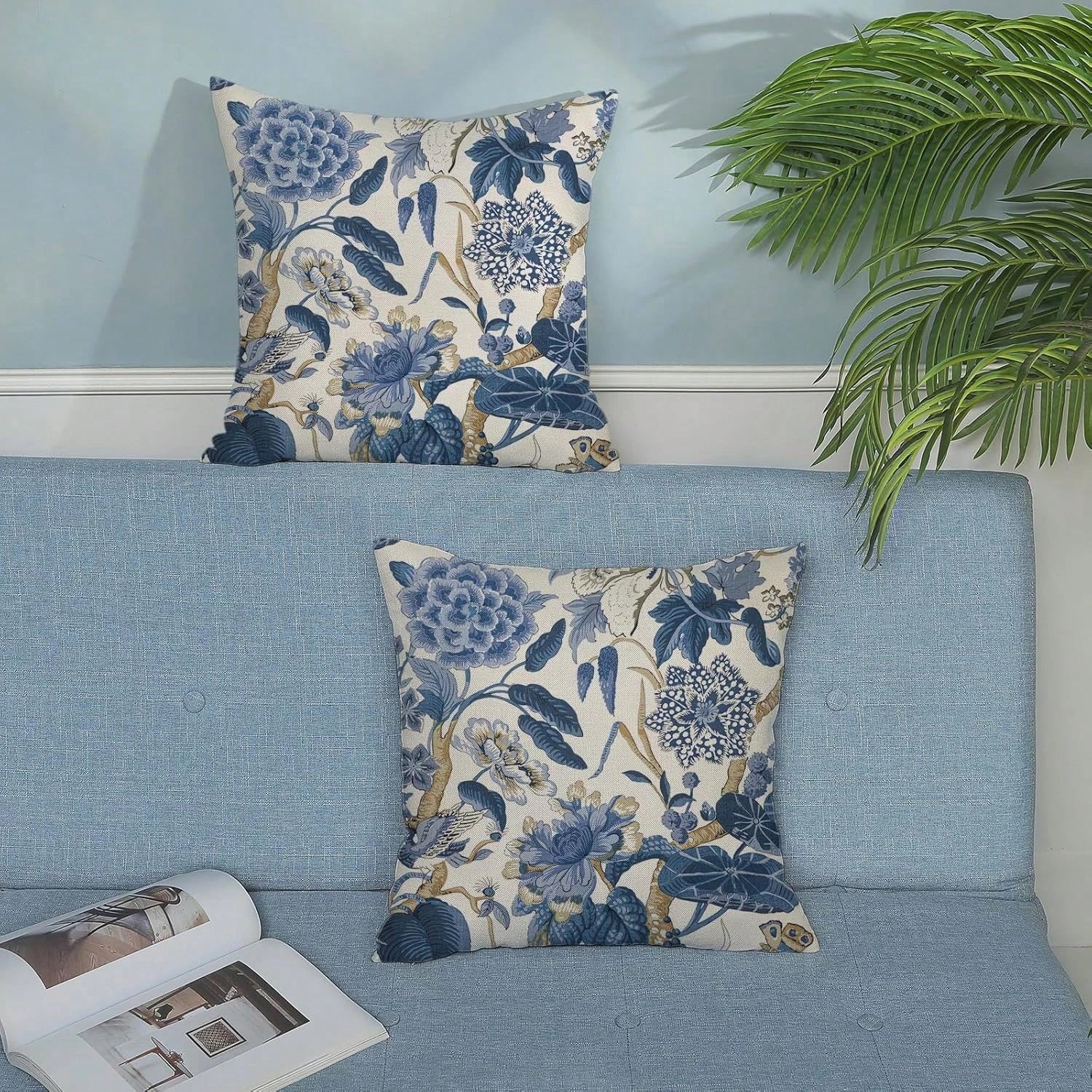 Floral patterned pillows on a blue sofa with a plant in the background