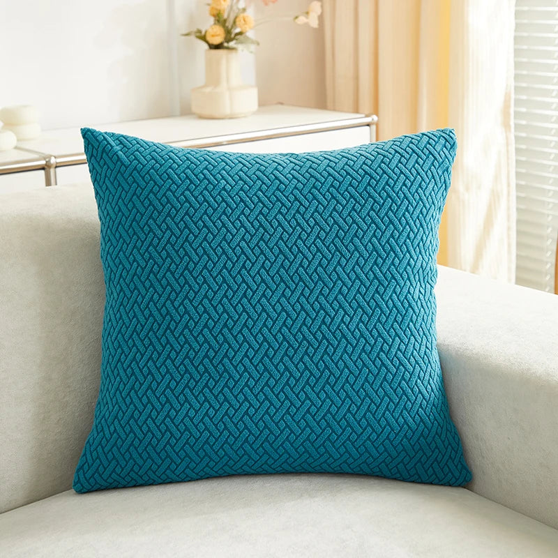Teal textured pillow on a light-colored sofa with a blurred background