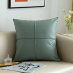 Green pillow on a beige sofa with a decorative tray and flowers in the background