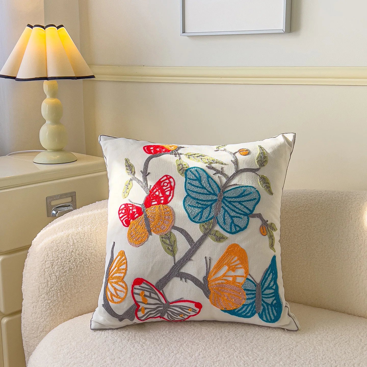 Decorative pillow with colorful butterfly design on a couch next to a lamp.
