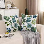 Floral-patterned pillows on a couch with a side table and decor items in the background.