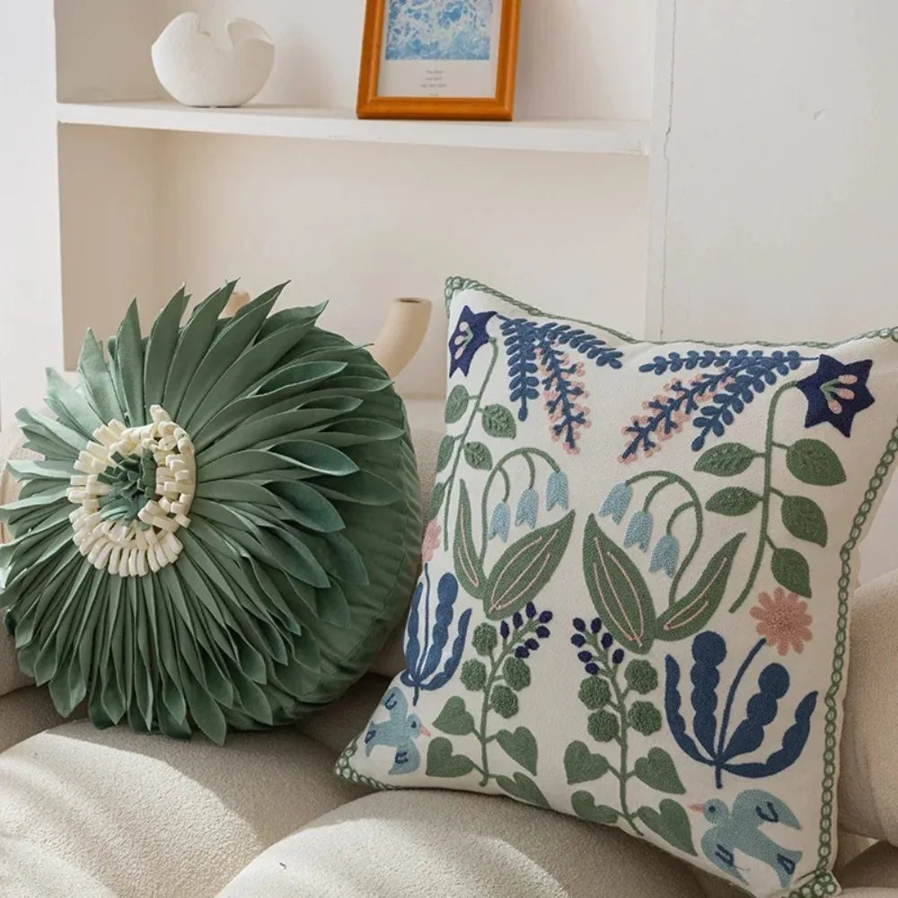 Decorative pillows on a sofa with a floral pattern and green leafy design.