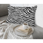 Zebra print pillow on a couch with a coffee cup and books on a tray.