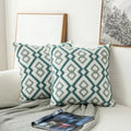Patterned teal and gray pillows on a white sofa with a magazine underneath.