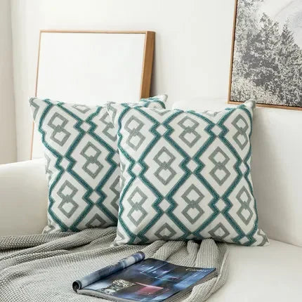 Patterned teal and gray pillows on a white sofa with a magazine underneath.