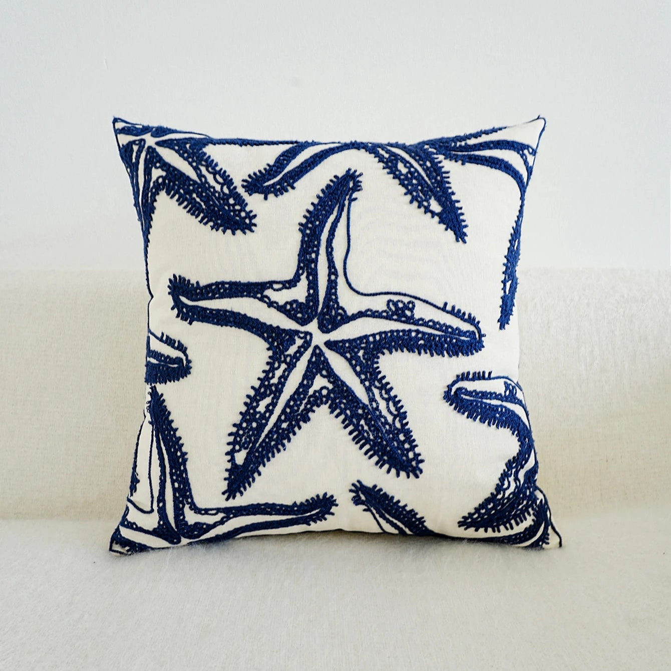 Navy starfish patterned pillow on a light gray background