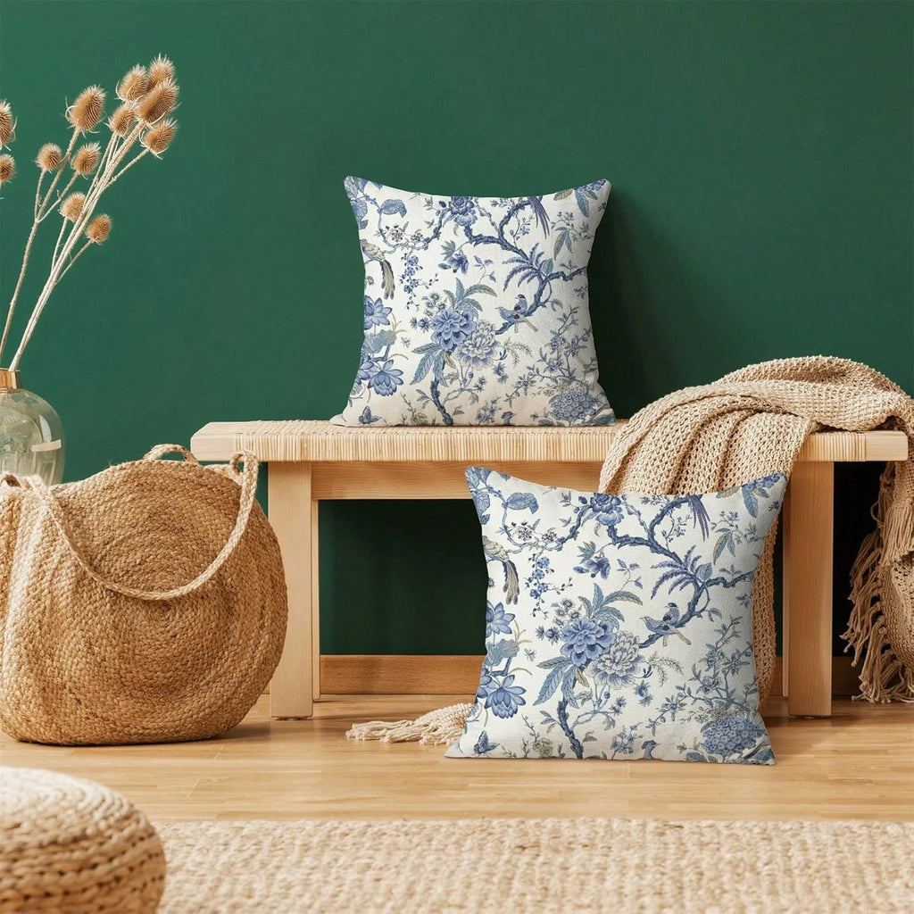 Floral-patterned pillows on a wooden bench against a green wall with a woven bag and decorative elements.