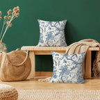 Floral-patterned pillows on a wooden bench against a green wall with a woven bag and decorative elements.