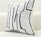 Decorative pillow with black abstract line design on a white background