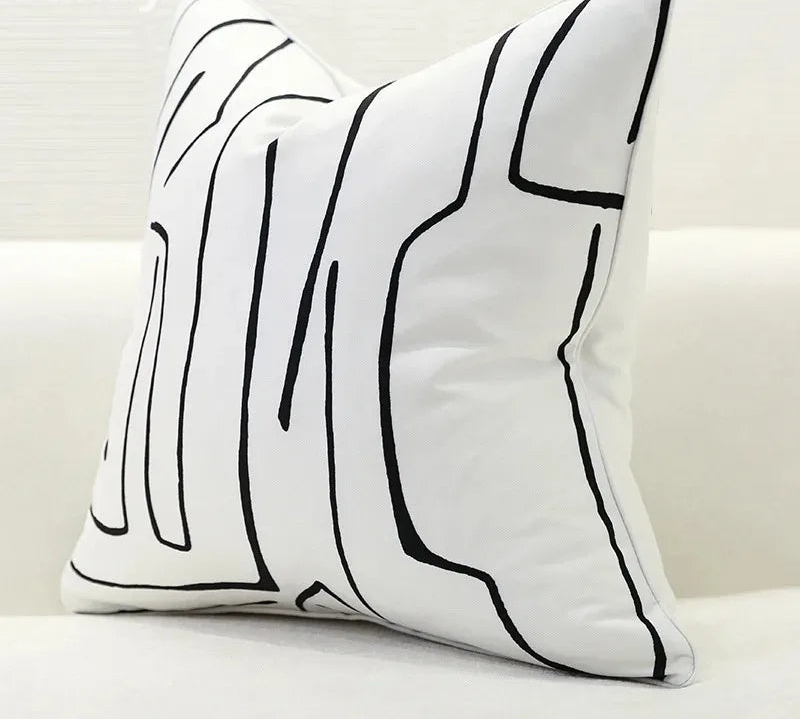 Decorative pillow with black abstract line design on a white background