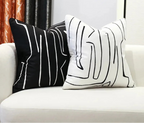 Two black and white abstract patterned pillows on a white couch with Bunny FiFi branding.