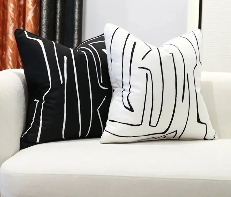 Two black and white abstract patterned pillows on a white couch with Bunny FiFi branding.
