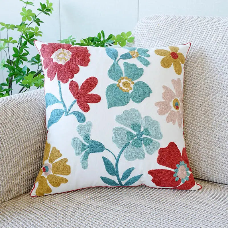 Floral-patterned pillow on a couch with a light blue wall and green plant in the background