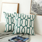 Two green and white patterned pillows on a couch with a magazine underneath.