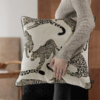Person holding a decorative pillow with leopard print design