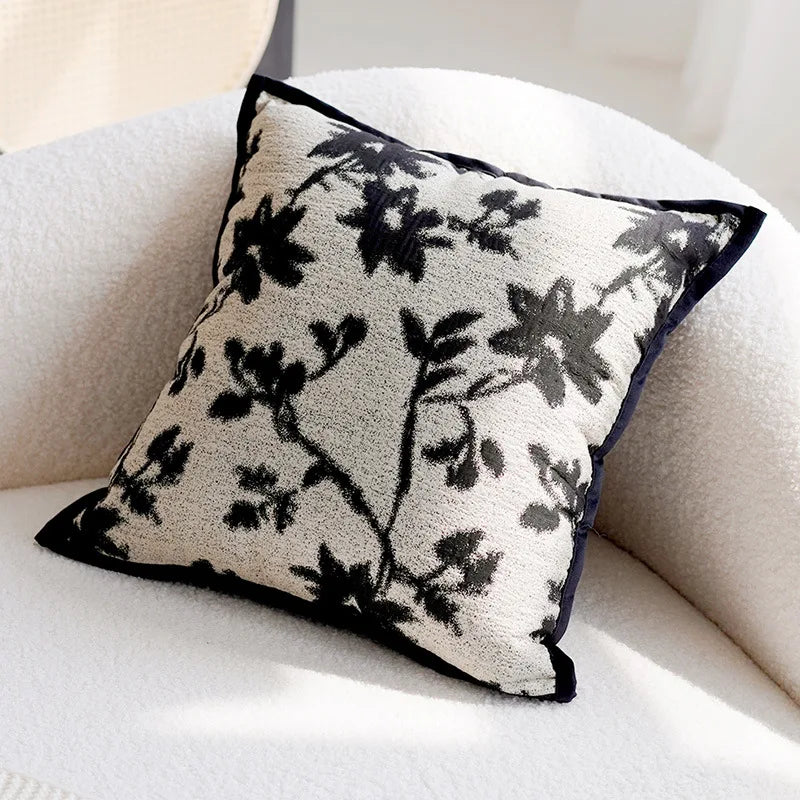 Decorative pillow with black floral pattern on a beige sofa