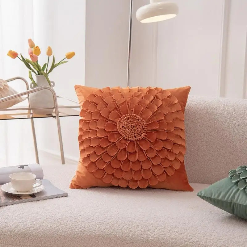 Orange floral velvet pillow cover with raised petal design on couch