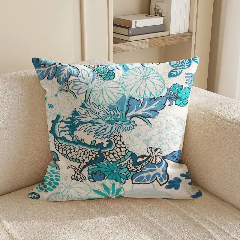 Decorative pillow with blue and green floral and dragon design on a beige couch.