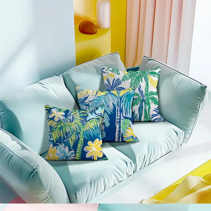 Light blue sofa with colorful palm leaf patterned cushions against a bright yellow wall.
