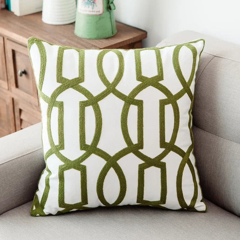 Green and white patterned pillow on a gray sofa with a wooden side table in the background.