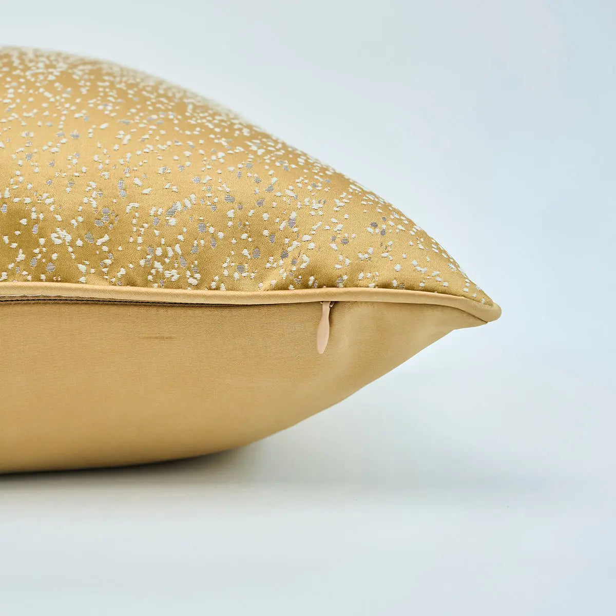 Gold pillow with glittery speckles on a light gray background