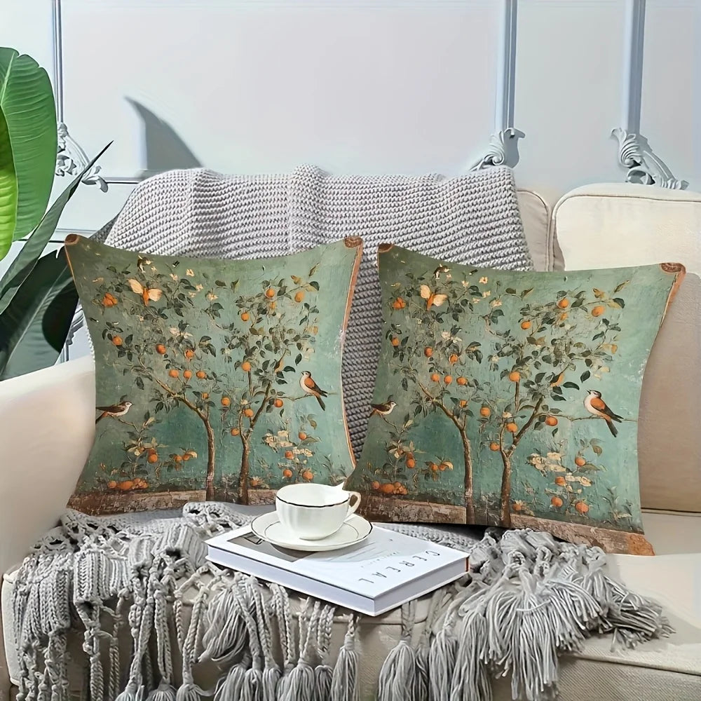 Decorative pillows with tree and bird pattern on a couch with a cup and saucer.