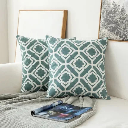 Patterned green and white cushions on a sofa with a magazine underneath.