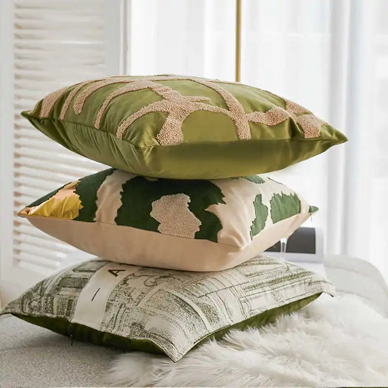 Three decorative pillows with different patterns stacked on a bed.
