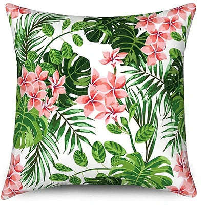 Decorative pillow with tropical floral design featuring pink flowers and green leaves on a white background.