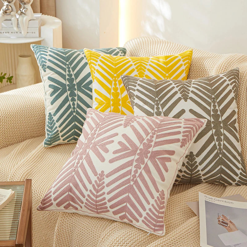 Four patterned pillows on a beige sofa with a neutral background
