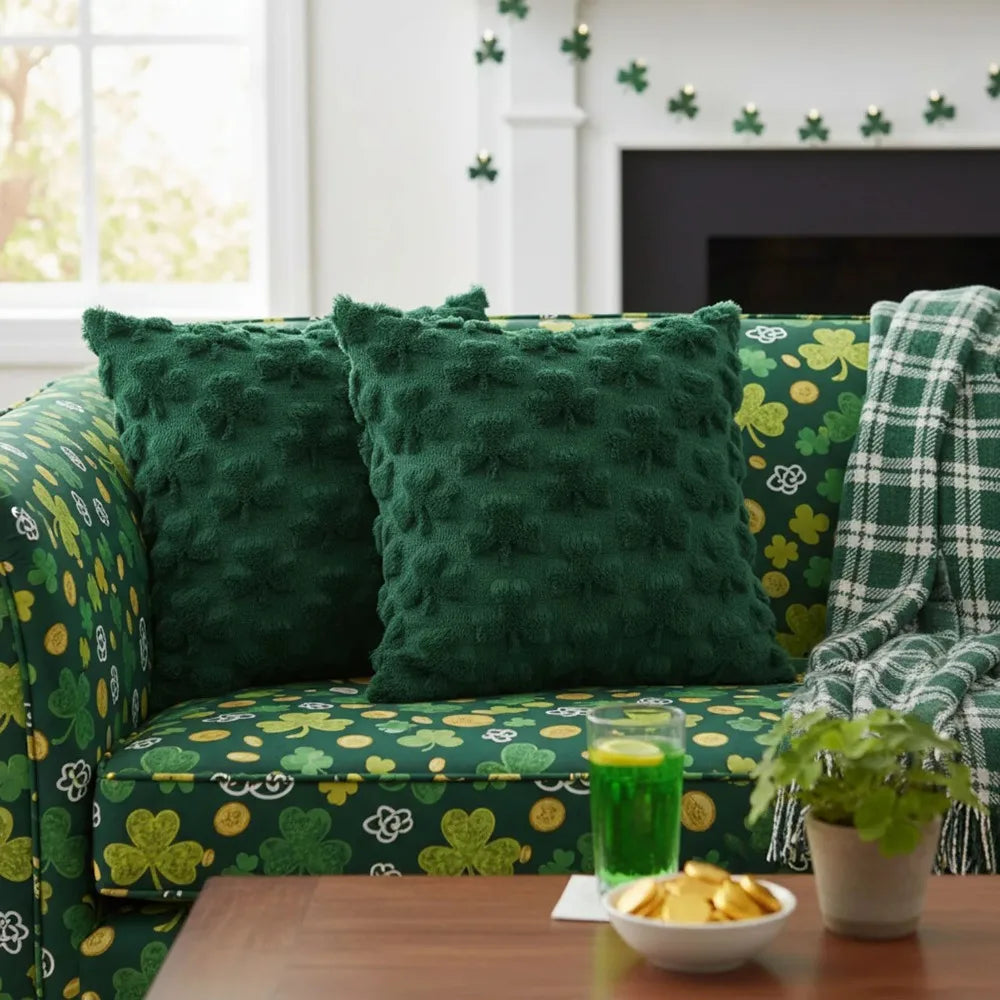 Green patterned couch with decorative pillows and a glass of green juice on a table.
