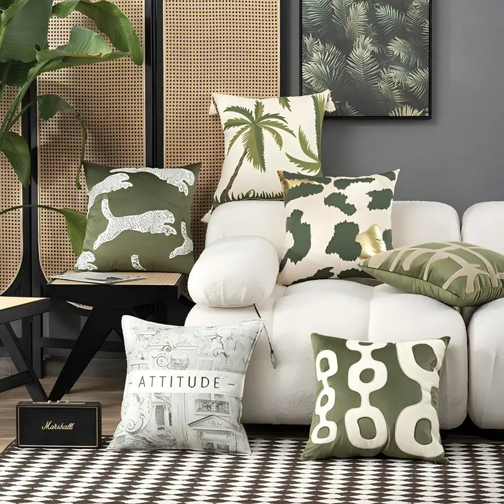 Decorative pillows on a white sofa with a plant and framed artwork in the background