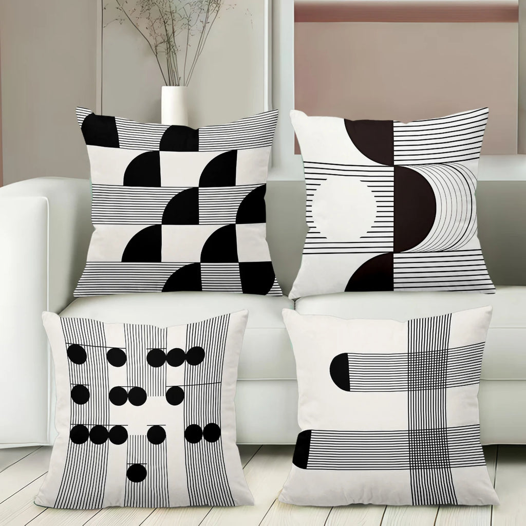 Set of four black and white patterned pillows on a white sofa.