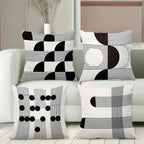 Set of four black and white patterned pillows on a white sofa.