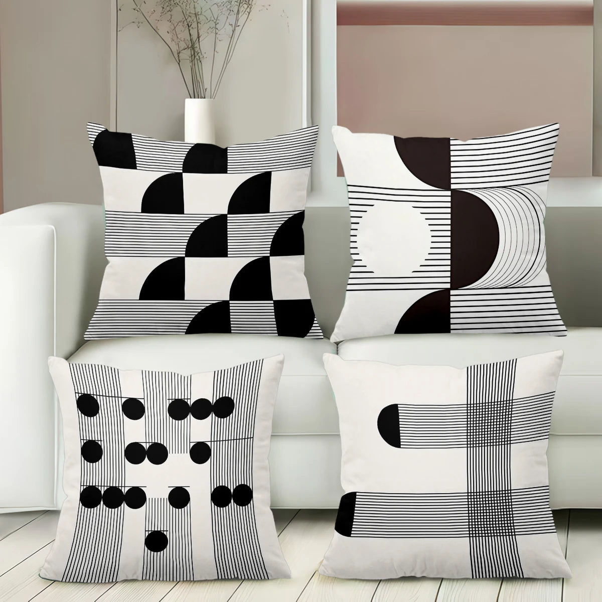 Set of four black and white patterned pillows on a white sofa.
