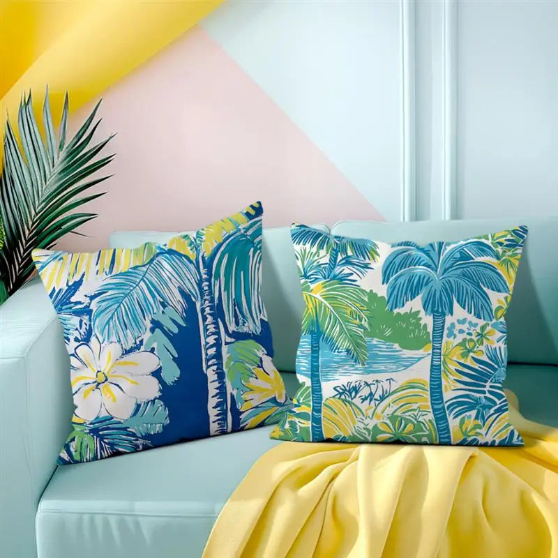 Tropical patterned pillows on a light blue sofa with a yellow blanket and leaf decoration.