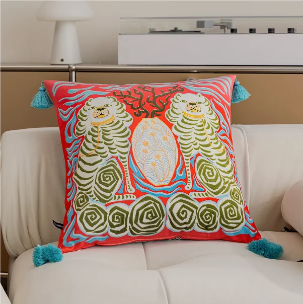 Decorative pillow with a colorful design of parrots on a beige sofa.