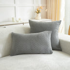 Two gray woven pillows on a white sofa with a neutral background