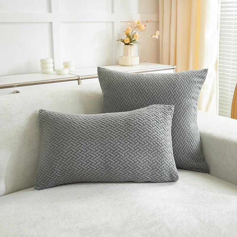 Two gray woven pillows on a white sofa with a neutral background