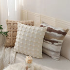 Three decorative pillows on a sofa with a neutral color palette.