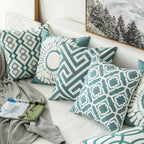 Patterned teal and white cushions on a sofa with a magazine and blanket.