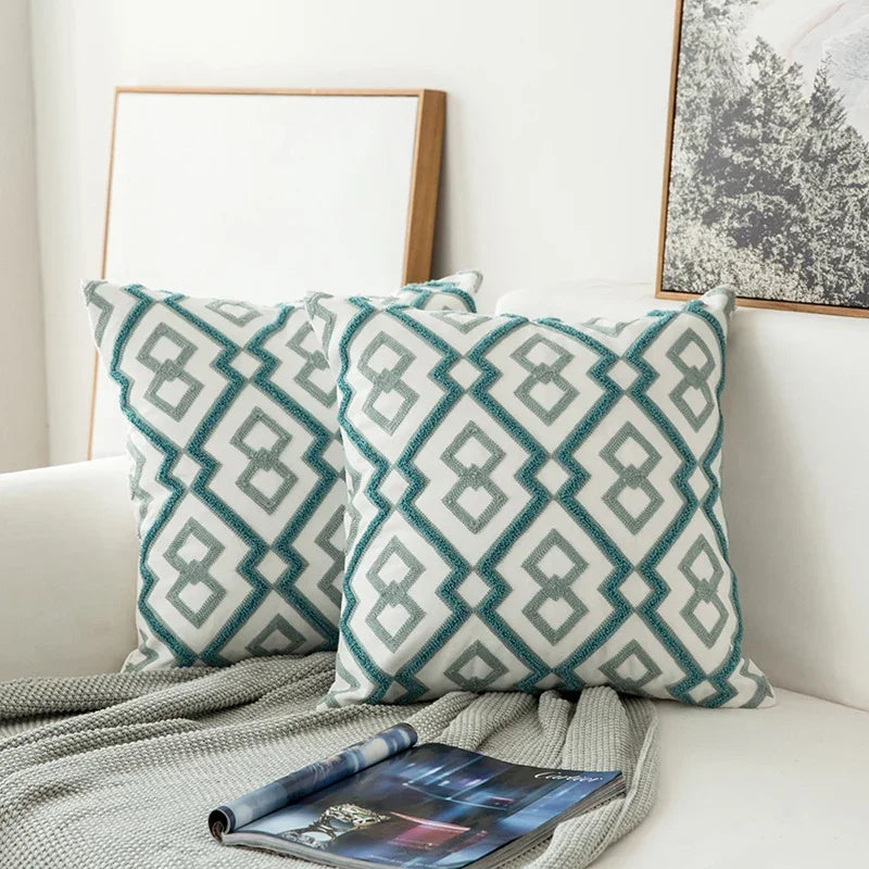 Patterned teal and gray pillows on a white sofa with a magazine underneath.