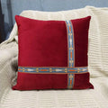 Red pillow with decorative band on a textured surface