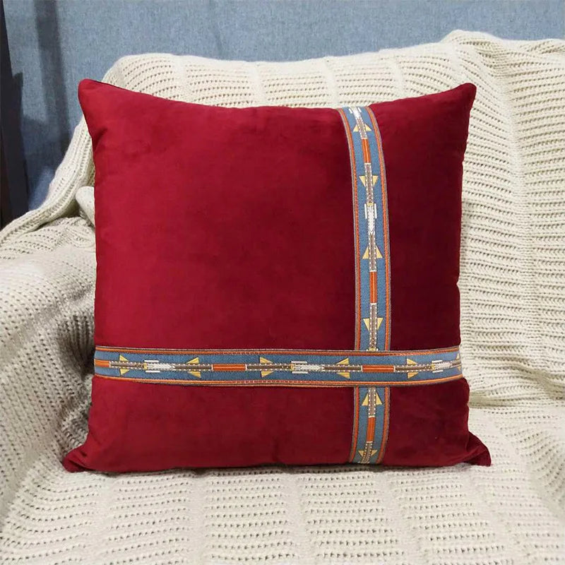 Red pillow with decorative band on a textured surface